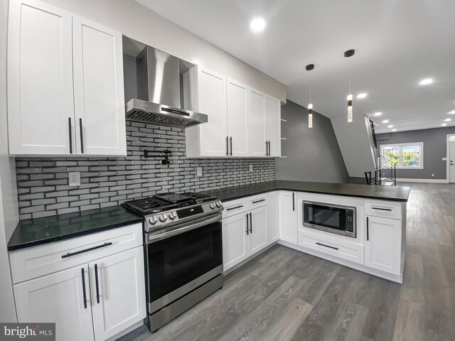 4827 N Warnock St, Philadelphia, PA 19141 - kitchen with appliances with stainless steel finishes, wall chimney exhaust hood, dark countertops, a peninsula, and dark wood-style floors