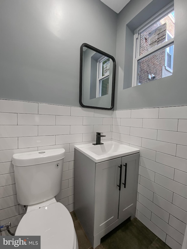 bathroom with vanity, toilet, and tile walls