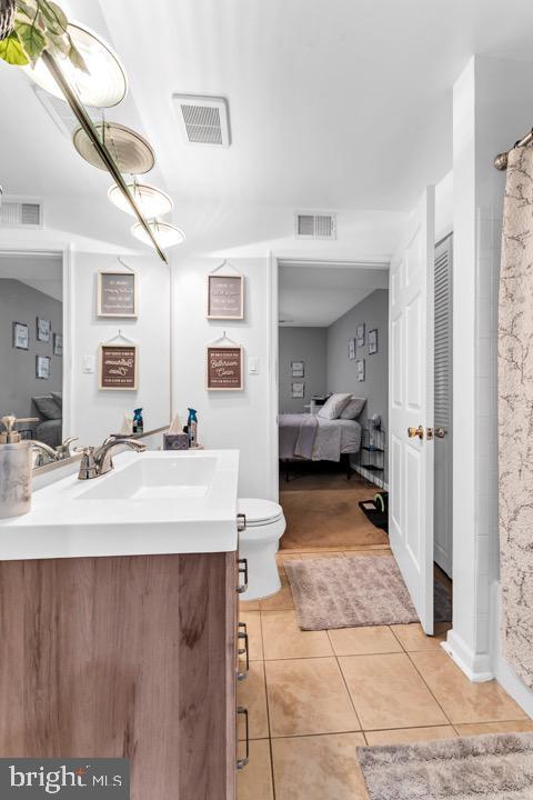 bathroom with tile patterned flooring, a shower with curtain, vanity, and toilet