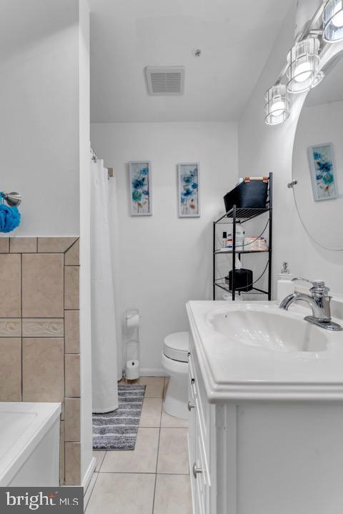 bathroom with tile patterned flooring, curtained shower, toilet, and sink