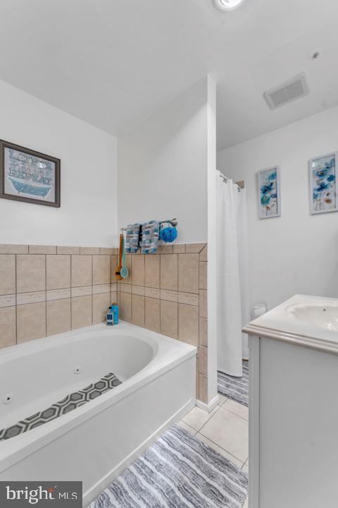 bathroom featuring tile patterned flooring, vanity, and a tub