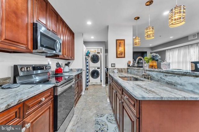 kitchen featuring sink, hanging light fixtures, stainless steel appliances, light stone counters, and stacked washer and dryer