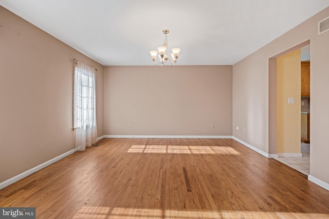 empty room with a chandelier and light wood-type flooring