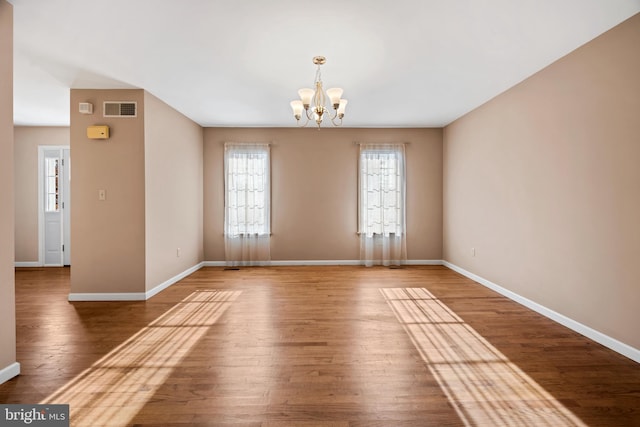 spare room with wood-type flooring and a chandelier