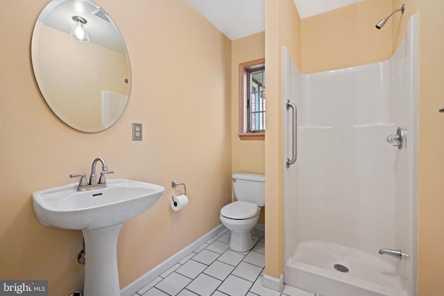 bathroom featuring tile patterned flooring, toilet, walk in shower, and sink