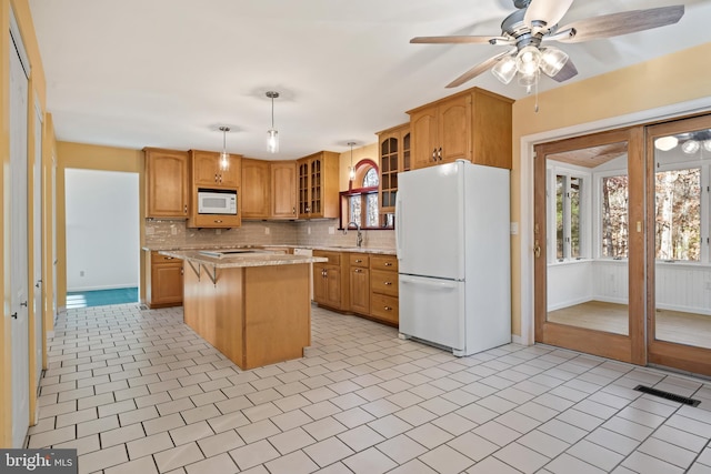 kitchen with sink, hanging light fixtures, white appliances, decorative backsplash, and a kitchen island