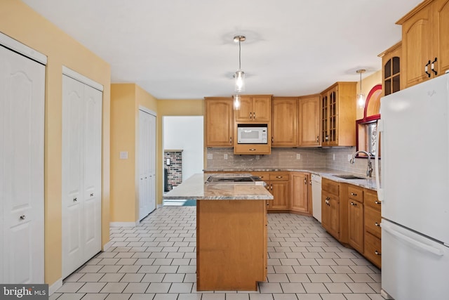 kitchen with light stone counters, white appliances, sink, decorative light fixtures, and a kitchen island