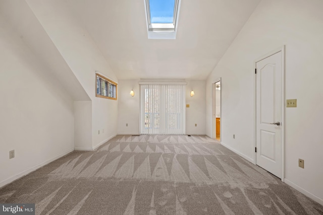 unfurnished living room featuring vaulted ceiling with skylight and light colored carpet