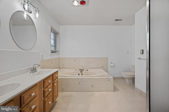 bathroom featuring tile patterned floors, tiled tub, vanity, and toilet