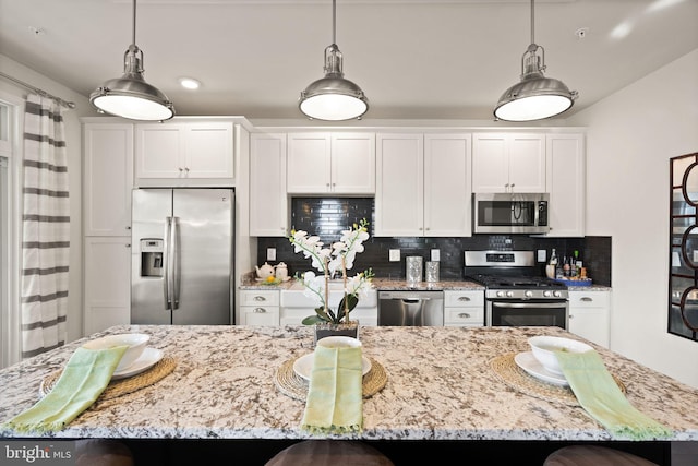 kitchen featuring a large island, backsplash, pendant lighting, white cabinets, and appliances with stainless steel finishes