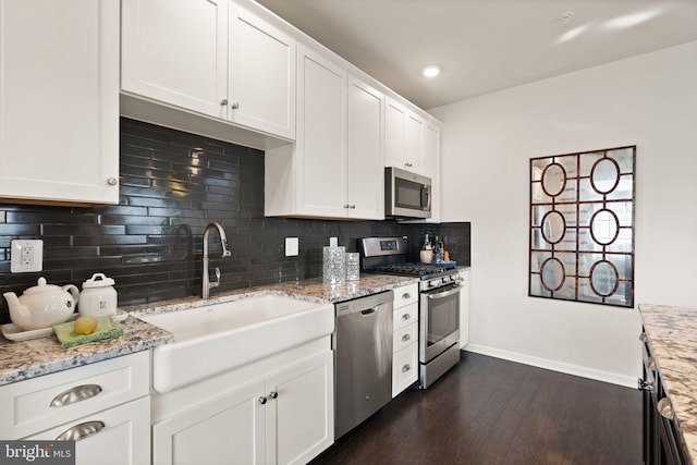 kitchen with dark wood-type flooring, white cabinets, sink, light stone countertops, and stainless steel appliances