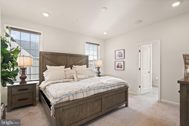 bedroom with connected bathroom and light colored carpet