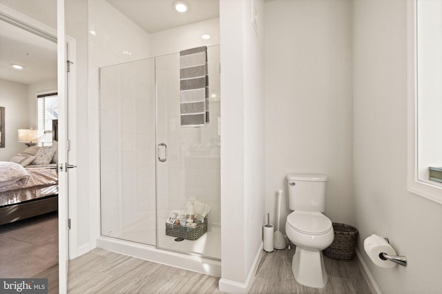 bathroom featuring toilet and a shower with door