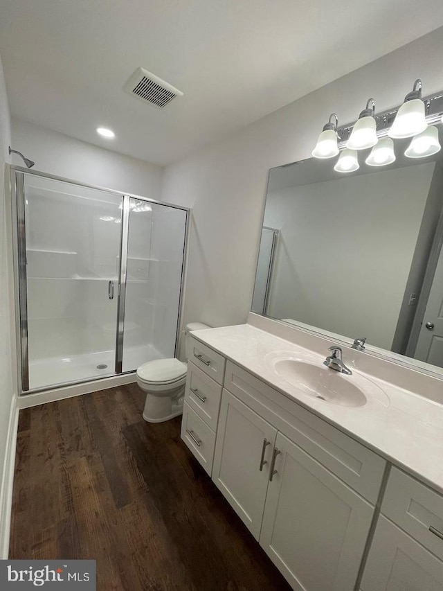 bathroom with hardwood / wood-style floors, vanity, toilet, and walk in shower