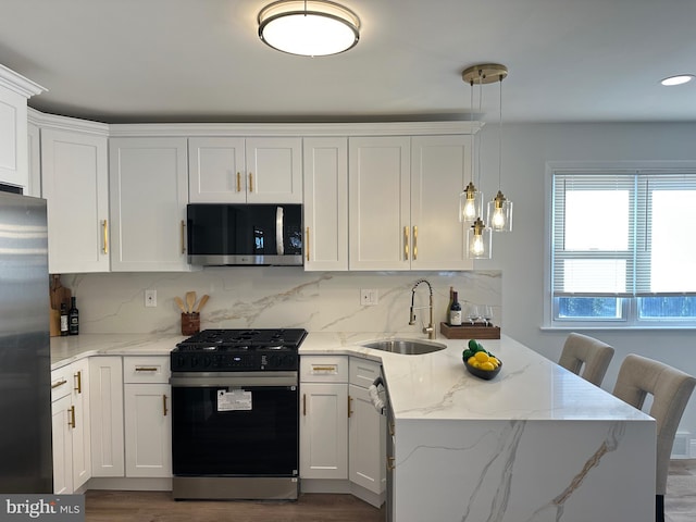 kitchen with white cabinets, pendant lighting, sink, and appliances with stainless steel finishes