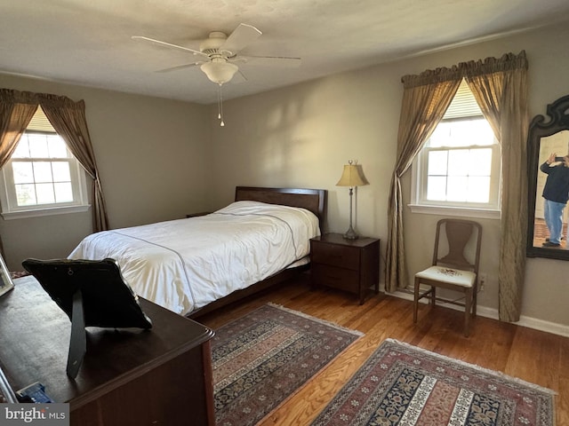 bedroom featuring hardwood / wood-style flooring, ceiling fan, and multiple windows