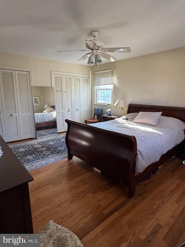 bedroom featuring multiple closets, ceiling fan, and wood-type flooring