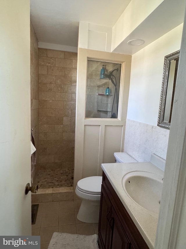 bathroom with tile patterned floors, vanity, toilet, and tiled shower