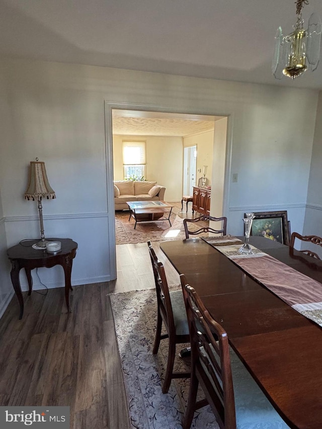 dining space with hardwood / wood-style floors and an inviting chandelier