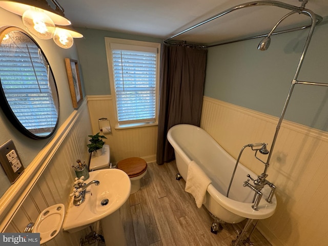 bathroom with a tub, sink, hardwood / wood-style floors, and toilet