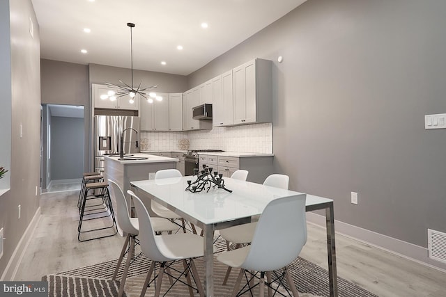 dining space featuring sink, a notable chandelier, and light wood-type flooring