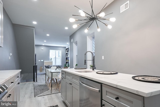 kitchen with gray cabinets, sink, a kitchen island with sink, stainless steel dishwasher, and light stone counters