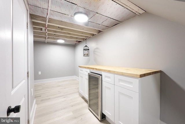 bar featuring pendant lighting, white cabinets, wooden counters, beverage cooler, and light wood-type flooring