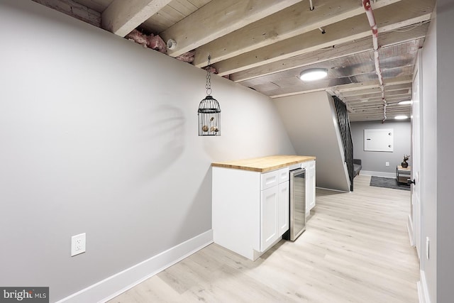 bar with pendant lighting, light hardwood / wood-style flooring, wooden counters, white cabinets, and beverage cooler