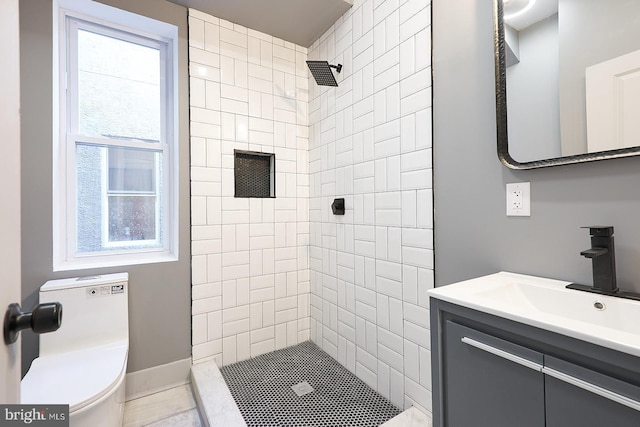 bathroom with tiled shower, vanity, and toilet