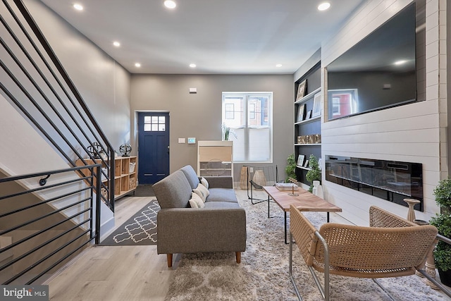 living room featuring built in shelves, a large fireplace, and light hardwood / wood-style floors