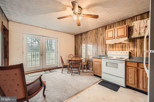 kitchen featuring white appliances, french doors, wooden walls, ceiling fan, and a textured ceiling