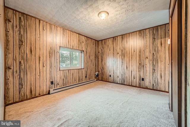 carpeted spare room featuring a textured ceiling, wooden walls, and a baseboard heating unit