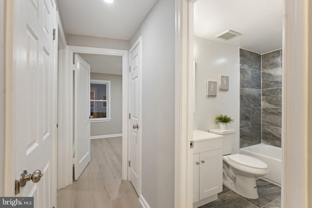 full bathroom with hardwood / wood-style floors, vanity, toilet, and tiled shower / bath