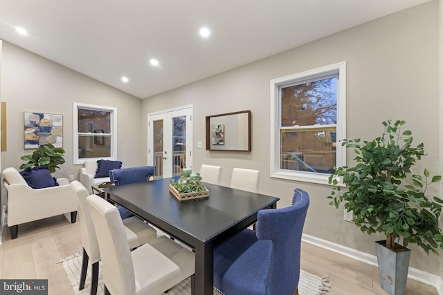 dining space with french doors, light hardwood / wood-style floors, and lofted ceiling