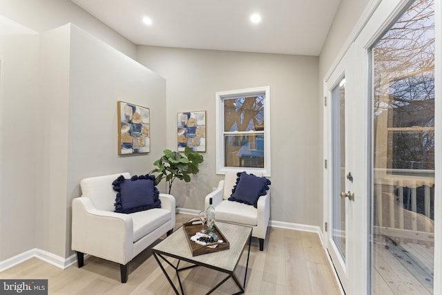 sitting room featuring french doors, light hardwood / wood-style floors, and vaulted ceiling