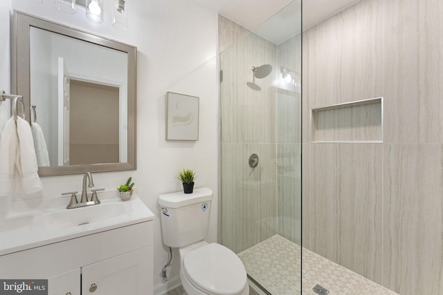 bathroom featuring a tile shower, vanity, and toilet