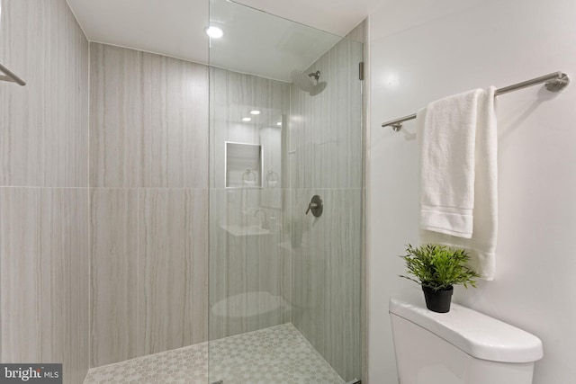 bathroom with a tile shower and toilet