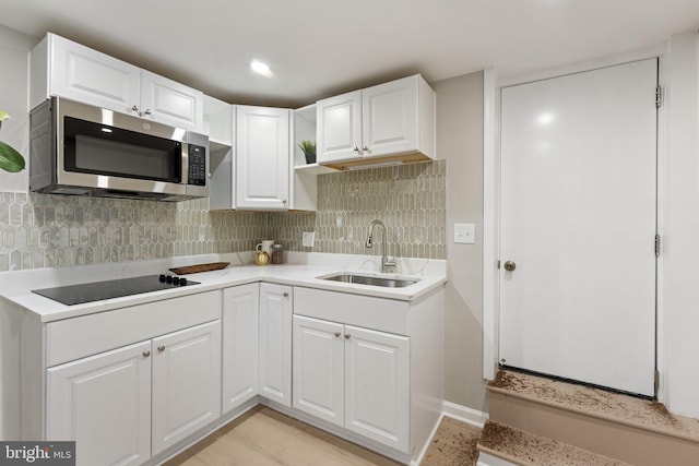 kitchen featuring decorative backsplash, black electric cooktop, sink, light hardwood / wood-style floors, and white cabinetry