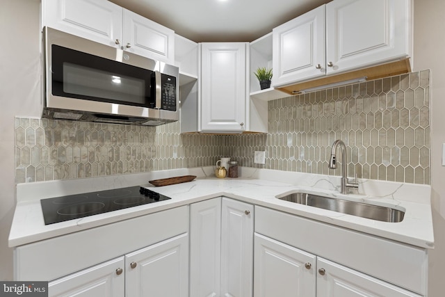 kitchen with black electric stovetop, white cabinetry, and sink