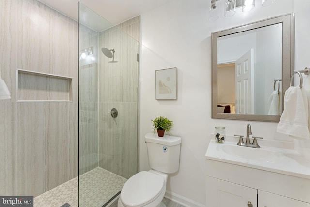 bathroom with a tile shower, vanity, and toilet