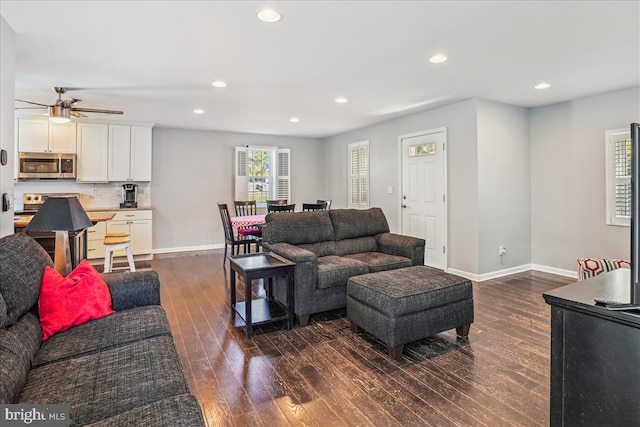 living room featuring ceiling fan and dark wood-type flooring