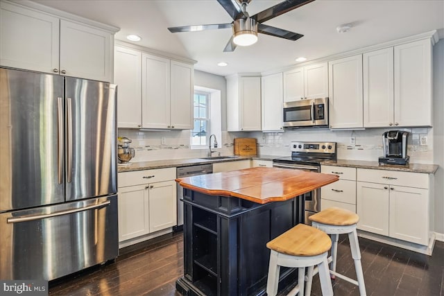 kitchen featuring sink, light stone counters, dark hardwood / wood-style floors, white cabinets, and appliances with stainless steel finishes