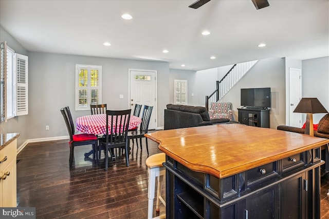 kitchen with a kitchen breakfast bar, ceiling fan, and dark wood-type flooring