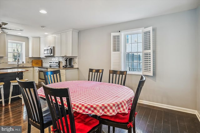 dining area featuring dark hardwood / wood-style flooring, ceiling fan, and sink