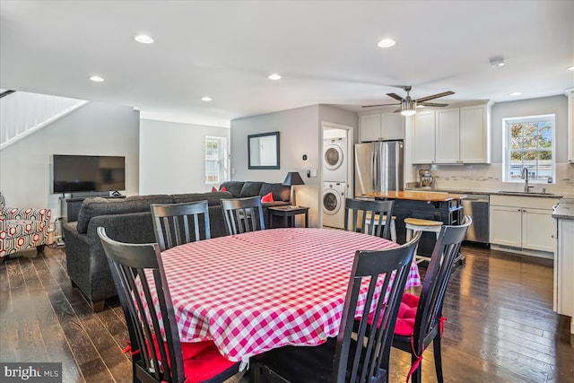 dining area with ceiling fan, sink, stacked washer / dryer, and dark wood-type flooring