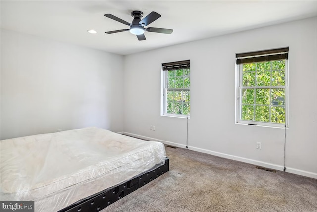 carpeted bedroom with multiple windows and ceiling fan