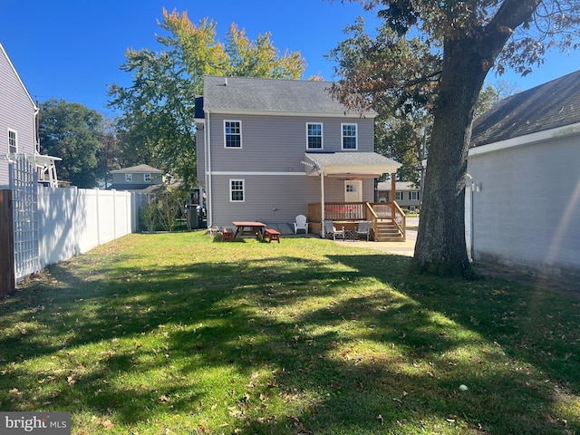 rear view of property featuring a lawn, cooling unit, and a deck