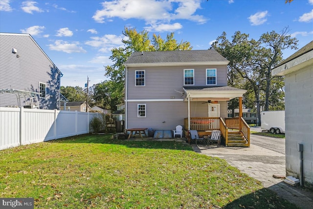 rear view of house featuring a yard and ceiling fan