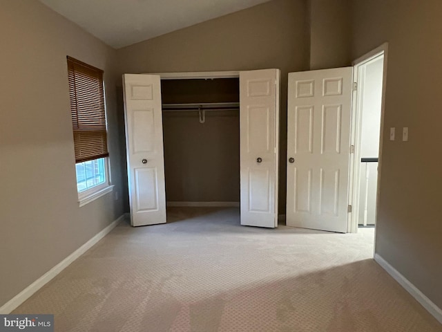 unfurnished bedroom with light carpet, a closet, and lofted ceiling