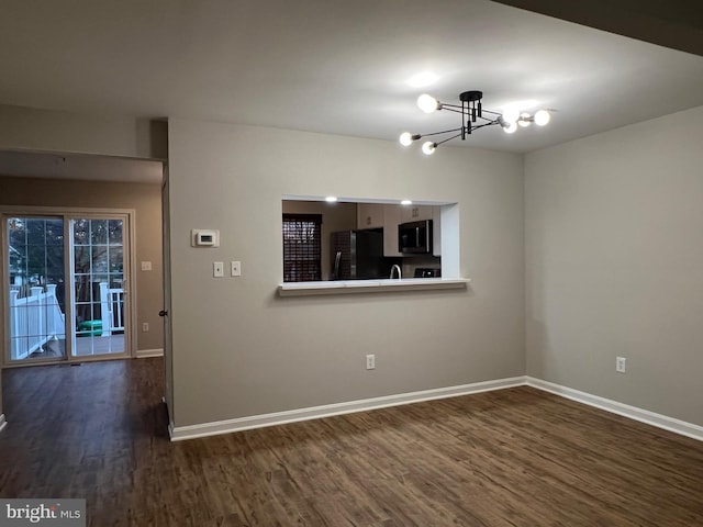 empty room with dark hardwood / wood-style floors and a chandelier